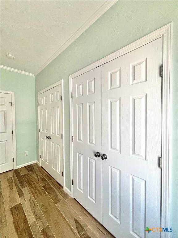 interior space with baseboards, wood finish floors, and crown molding