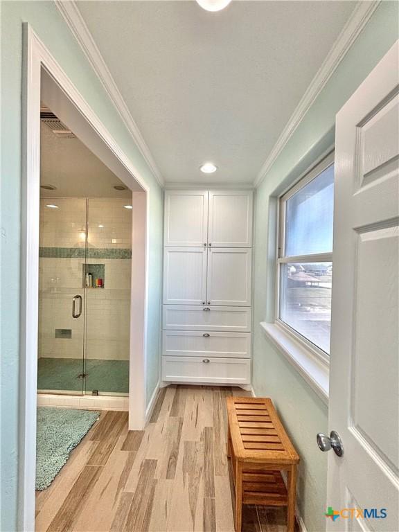 interior space with visible vents, ornamental molding, light wood-style flooring, and baseboards