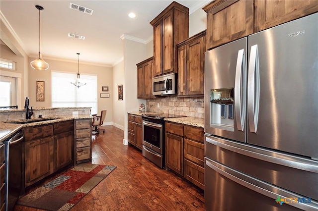 kitchen featuring crown molding, light stone countertops, decorative light fixtures, and stainless steel appliances