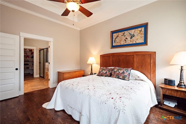 bedroom featuring dark wood-type flooring, ceiling fan, ornamental molding, and a tray ceiling