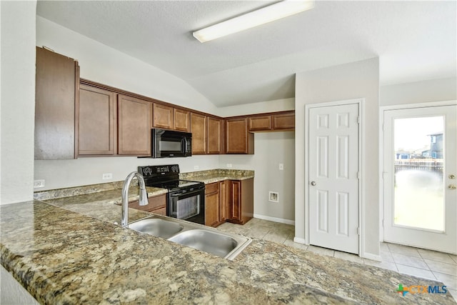 kitchen featuring kitchen peninsula, a healthy amount of sunlight, black appliances, and vaulted ceiling