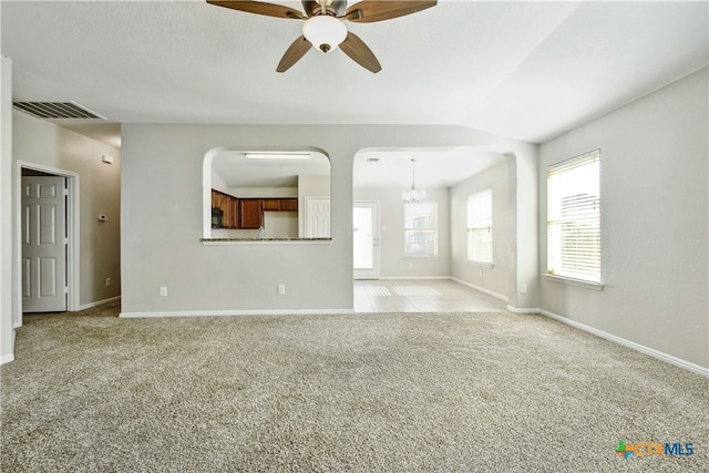 unfurnished living room featuring ceiling fan with notable chandelier, light colored carpet, and lofted ceiling