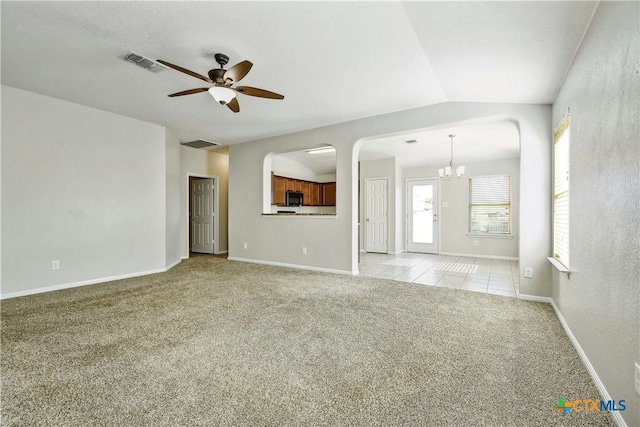 unfurnished living room featuring ceiling fan with notable chandelier, light carpet, and vaulted ceiling