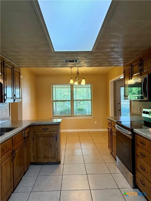 3002 Lois Cir, Copperas Cove, TX 76522 - kitchen with appliances with stainless steel finishes, light tile patterned floors, a skylight, pendant lighting, and brown cabinets