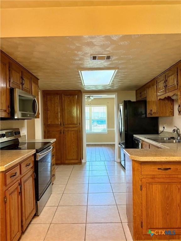 3002 Lois Cir, Copperas Cove, TX 76522 - kitchen with appliances with stainless steel finishes, brown cabinets, and light tile patterned floors