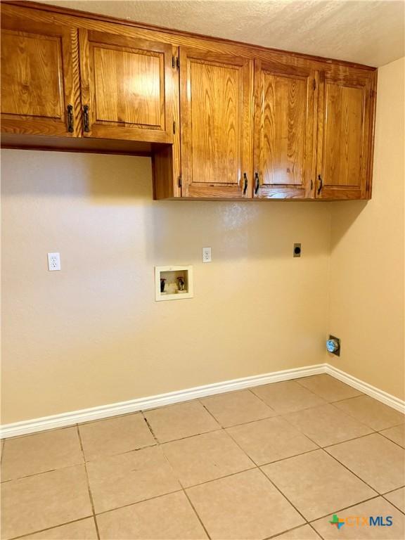 3002 Lois Cir, Copperas Cove, TX 76522 - laundry room with cabinet space, hookup for a washing machine, hookup for an electric dryer, light tile patterned floors, and a textured ceiling