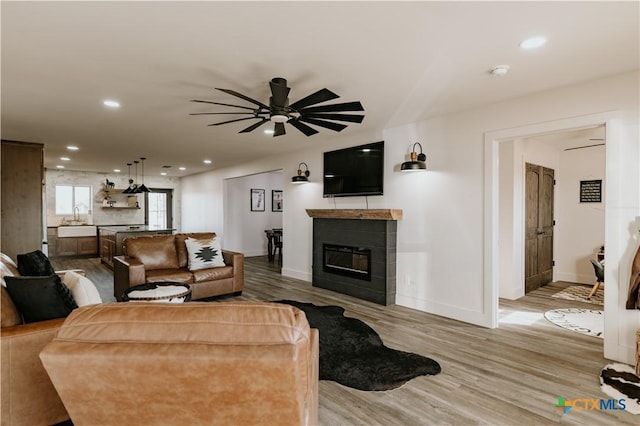 living room with wood-type flooring, ceiling fan, and sink