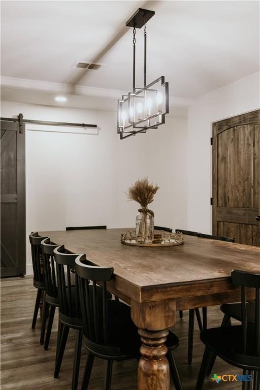 dining area with hardwood / wood-style flooring, a barn door, and a chandelier