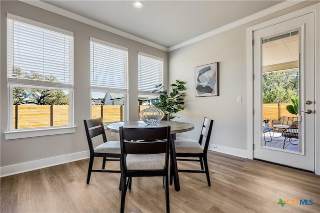 dining area featuring baseboards, light wood finished floors, and crown molding