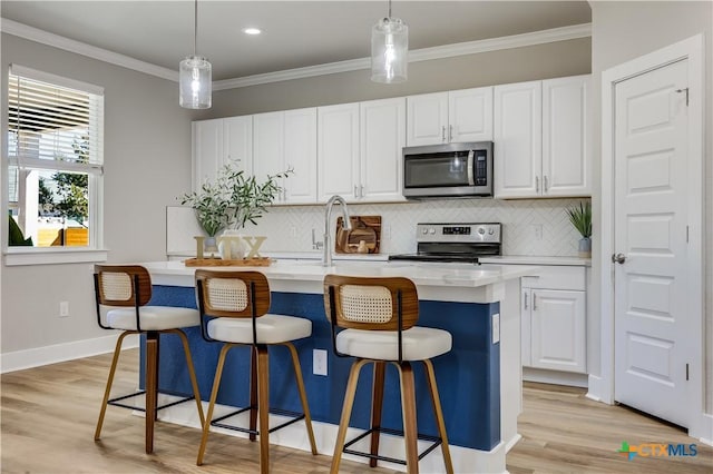 kitchen with white cabinetry, a kitchen island with sink, appliances with stainless steel finishes, and light countertops