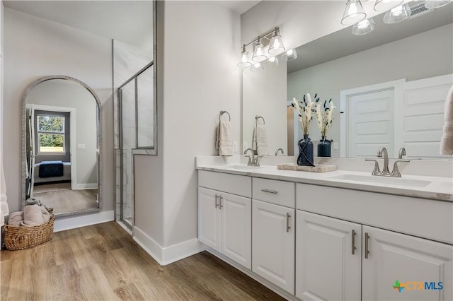 ensuite bathroom with double vanity, visible vents, a sink, and wood finished floors