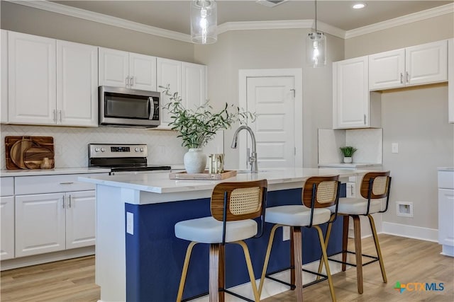 kitchen featuring a kitchen island with sink, stainless steel appliances, and light countertops