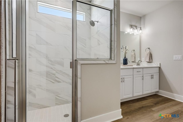 full bath with a stall shower, baseboards, wood finished floors, and vanity