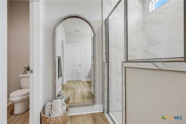 full bath with toilet, a stall shower, visible vents, and wood finished floors