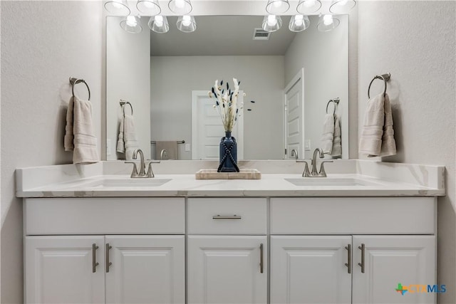 full bath with double vanity, a sink, and visible vents