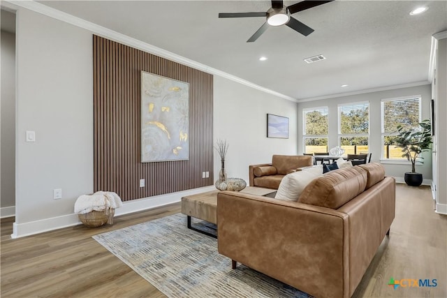 living area featuring light wood finished floors, ornamental molding, and visible vents