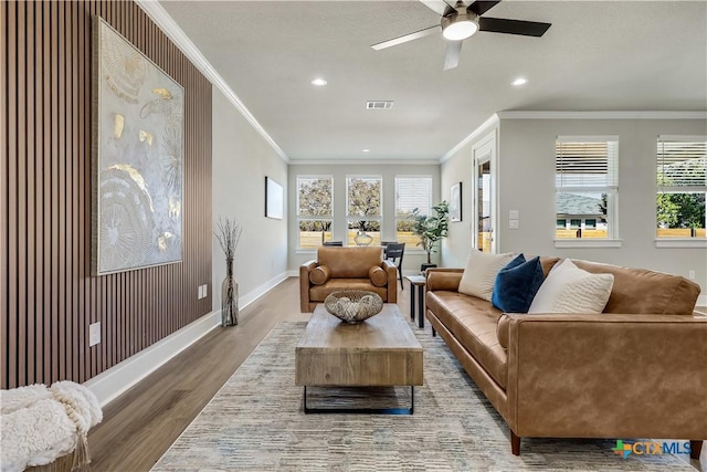 living room featuring ornamental molding, wood finished floors, visible vents, and baseboards