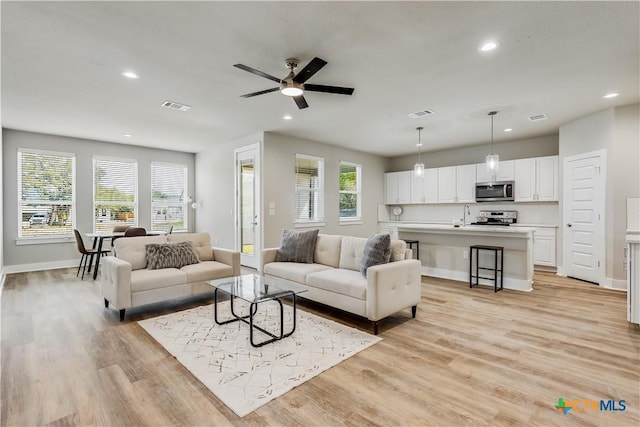 living room with plenty of natural light, sink, and light hardwood / wood-style flooring