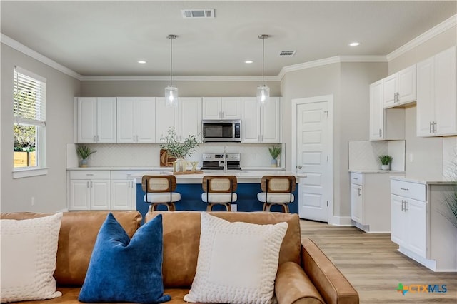 kitchen with appliances with stainless steel finishes, pendant lighting, light countertops, and visible vents