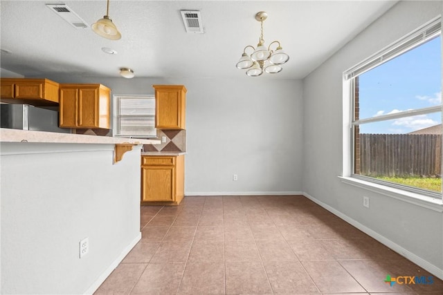 1212 Trailboss Dr, Killeen, TX 76549 - kitchen with hanging light fixtures, a chandelier, light countertops, freestanding refrigerator, and light tile patterned flooring