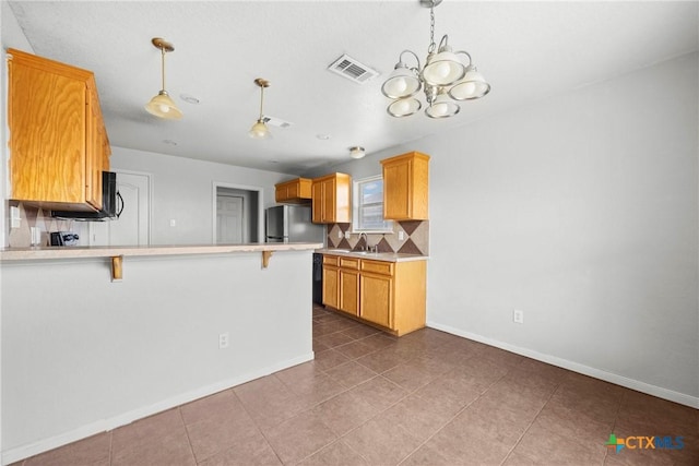 1212 Trailboss Dr, Killeen, TX 76549 - kitchen featuring a peninsula, a chandelier, tasteful backsplash, light countertops, and a kitchen breakfast bar