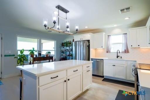 kitchen featuring visible vents, white cabinets, a notable chandelier, a sink, and stainless steel appliances