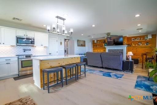 kitchen featuring light countertops, a center island, white cabinetry, a kitchen bar, and stainless steel appliances