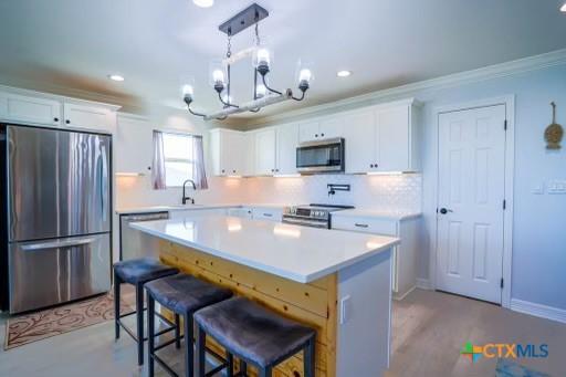 kitchen featuring a breakfast bar, an inviting chandelier, light countertops, appliances with stainless steel finishes, and a sink