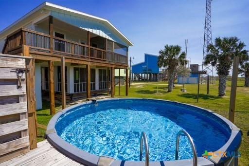 view of pool featuring a wooden deck and a lawn