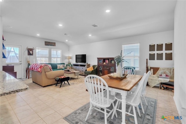 dining room with light tile patterned floors, vaulted ceiling, and a healthy amount of sunlight