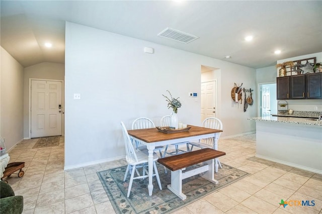 tiled dining area featuring vaulted ceiling