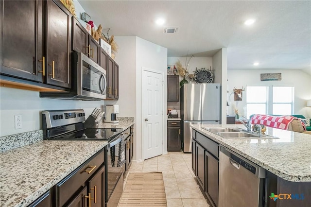 kitchen featuring dark brown cabinetry, sink, a center island with sink, light tile patterned floors, and appliances with stainless steel finishes