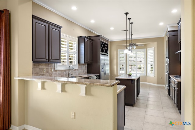 kitchen featuring a kitchen bar, sink, decorative backsplash, kitchen peninsula, and a center island