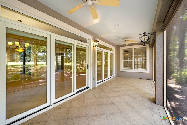 unfurnished sunroom with ceiling fan with notable chandelier