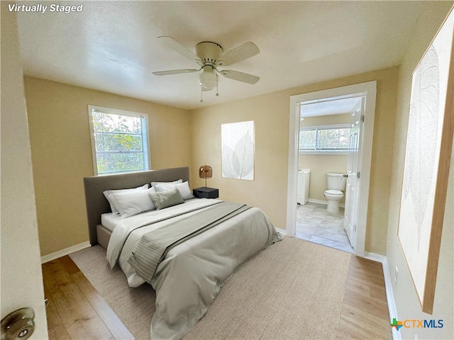 bedroom with connected bathroom, multiple windows, and light hardwood / wood-style flooring