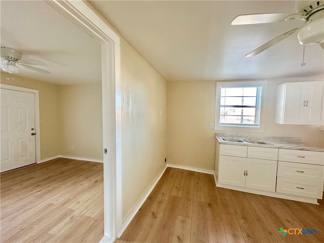 kitchen featuring white cabinets, light wood-type flooring, ceiling fan, and sink