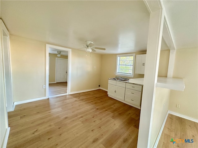 interior space featuring ceiling fan, light hardwood / wood-style flooring, and white cabinets