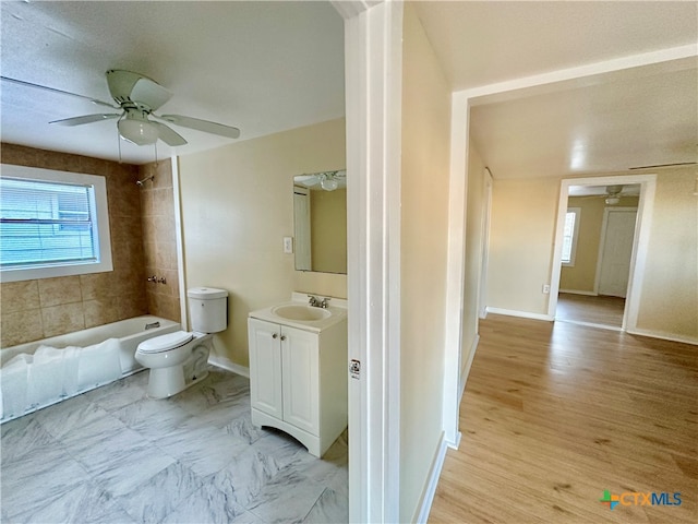 full bathroom featuring vanity, ceiling fan, tiled shower / bath combo, toilet, and wood-type flooring