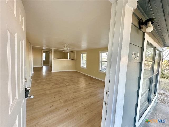 unfurnished living room featuring ceiling fan, plenty of natural light, and light hardwood / wood-style floors