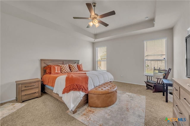 carpeted bedroom with ceiling fan and a raised ceiling