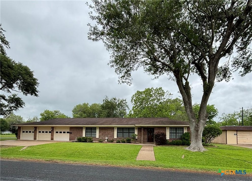 ranch-style home with concrete driveway, an attached garage, a front lawn, and brick siding
