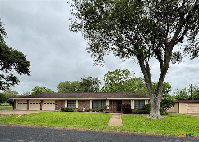ranch-style home with concrete driveway, an attached garage, a front lawn, and brick siding