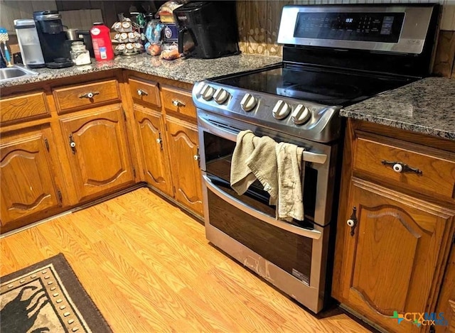 kitchen featuring stone counters, double oven range, and light hardwood / wood-style flooring