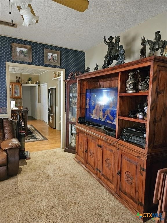 living room with a textured ceiling, light hardwood / wood-style floors, and ceiling fan