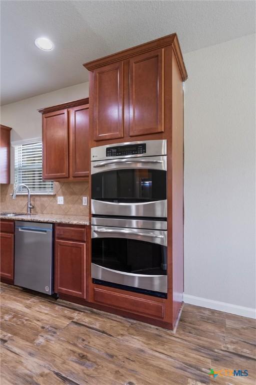 3903 Scenic Trail Dr, Harker Heights, TX 76548 - kitchen featuring stainless steel appliances, a sink, wood finished floors, decorative backsplash, and baseboards