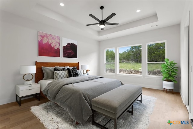 bedroom featuring hardwood / wood-style floors, ceiling fan, and a tray ceiling