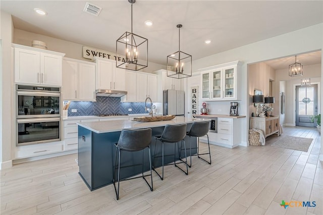1308 Dancing Oak Ln, San Marcos, TX 78666 - kitchen with double oven, freestanding refrigerator, a chandelier, tasteful backsplash, and light wood finished floors