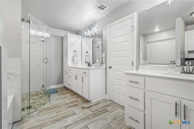 bathroom featuring a shower with shower door and vanity