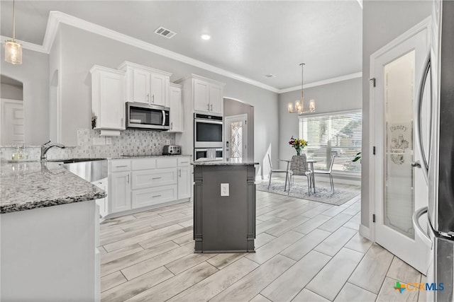 kitchen with hanging light fixtures, stainless steel appliances, and white cabinetry