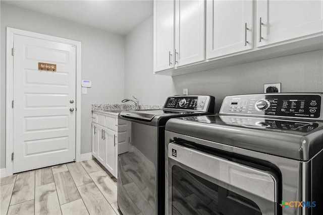 clothes washing area with sink, separate washer and dryer, and cabinets